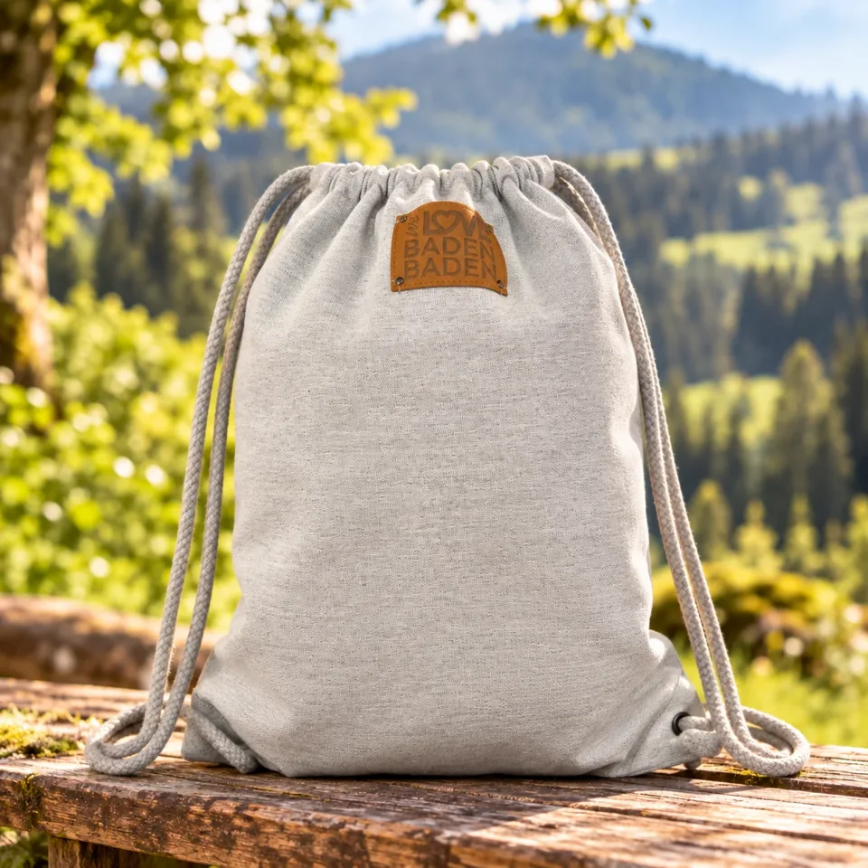 Grauer Rucksack mit Baden-Baden-Motiv vor Waldkulisse